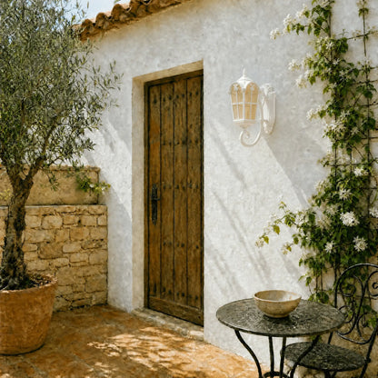 Lanterne murale extérieure blanche posée près d'une porte en bois sur un patio provençal | Delvanie