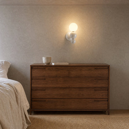 Applique murale boule blanche allumée au-dessus d'une commode en noyer dans une chambre | Delvanie