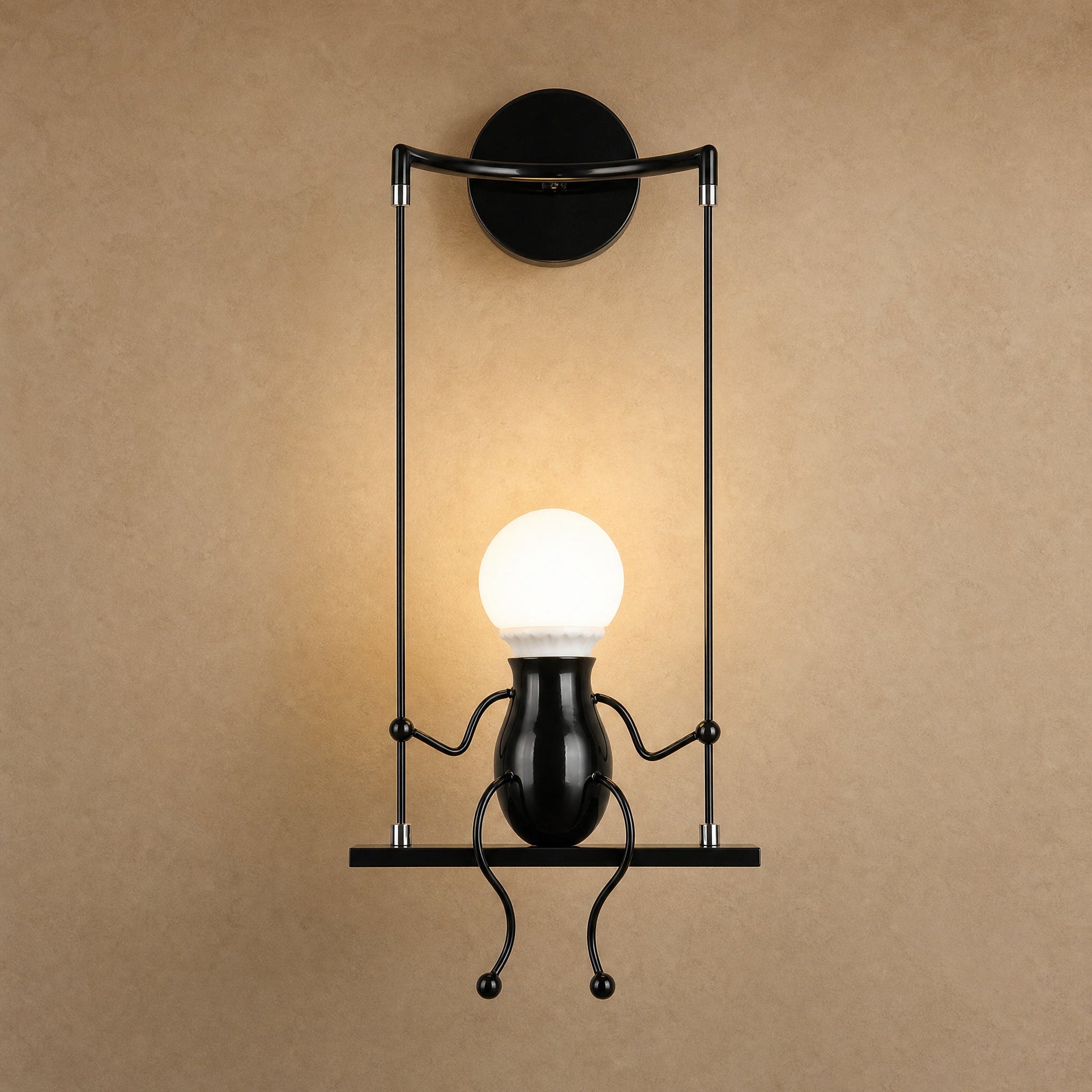 Applique murale noire Girotta, petit personnage assis sur sa balançoire, ampoule globe allumée | Delvanie