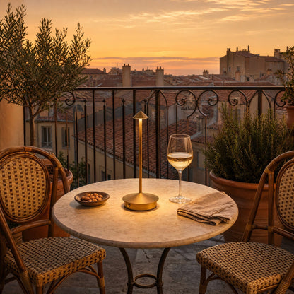Lampe de table sans fil doree allumee sur une table de terrasse au coucher du soleil | Delvanie