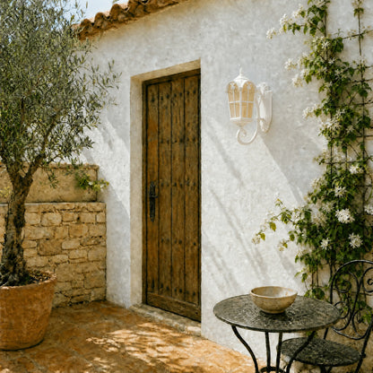 Lanterne murale extérieure blanche posée près d'une porte en bois sur un patio provençal | Delvanie